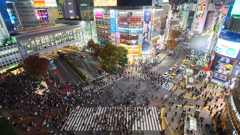 混雑する駅で多くの人がスマートフォンを操作している